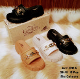 A collection of flip-flops presented in front of a shoebox, with two pairs in black and beige colors, and decorative metal chains on the straps.